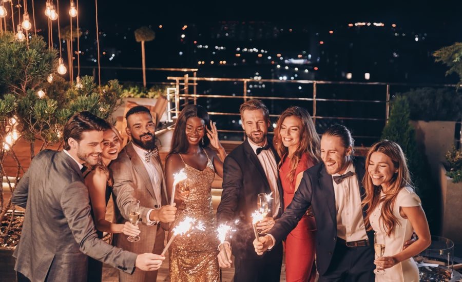 Well-dressed group of friends with sparklers at rooftop New Year's party