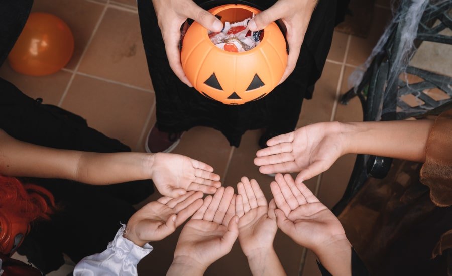 Kids in Halloween costumes reaching out their hands for candy