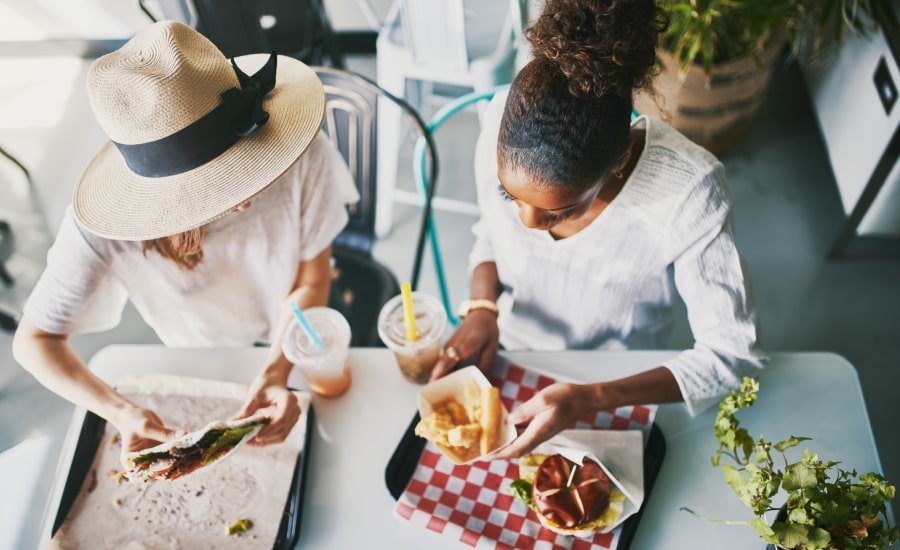 Two women sharing vegan food at restaurant