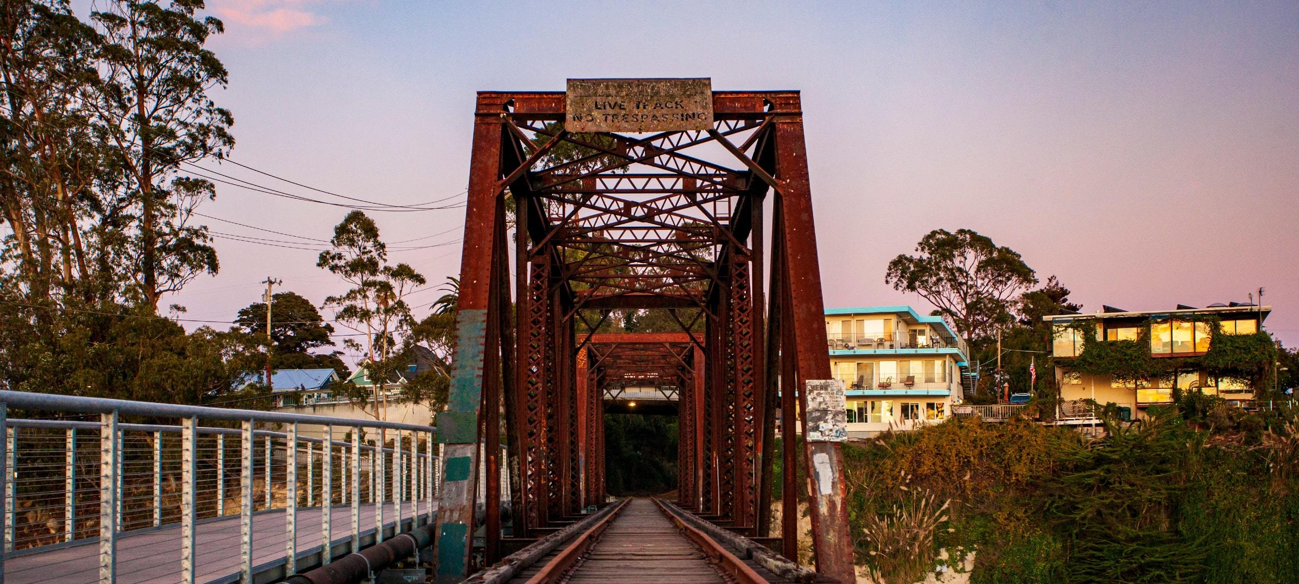 Abandoned bridge during sunset in Santa Cruz, CA with luxury homes on hillside