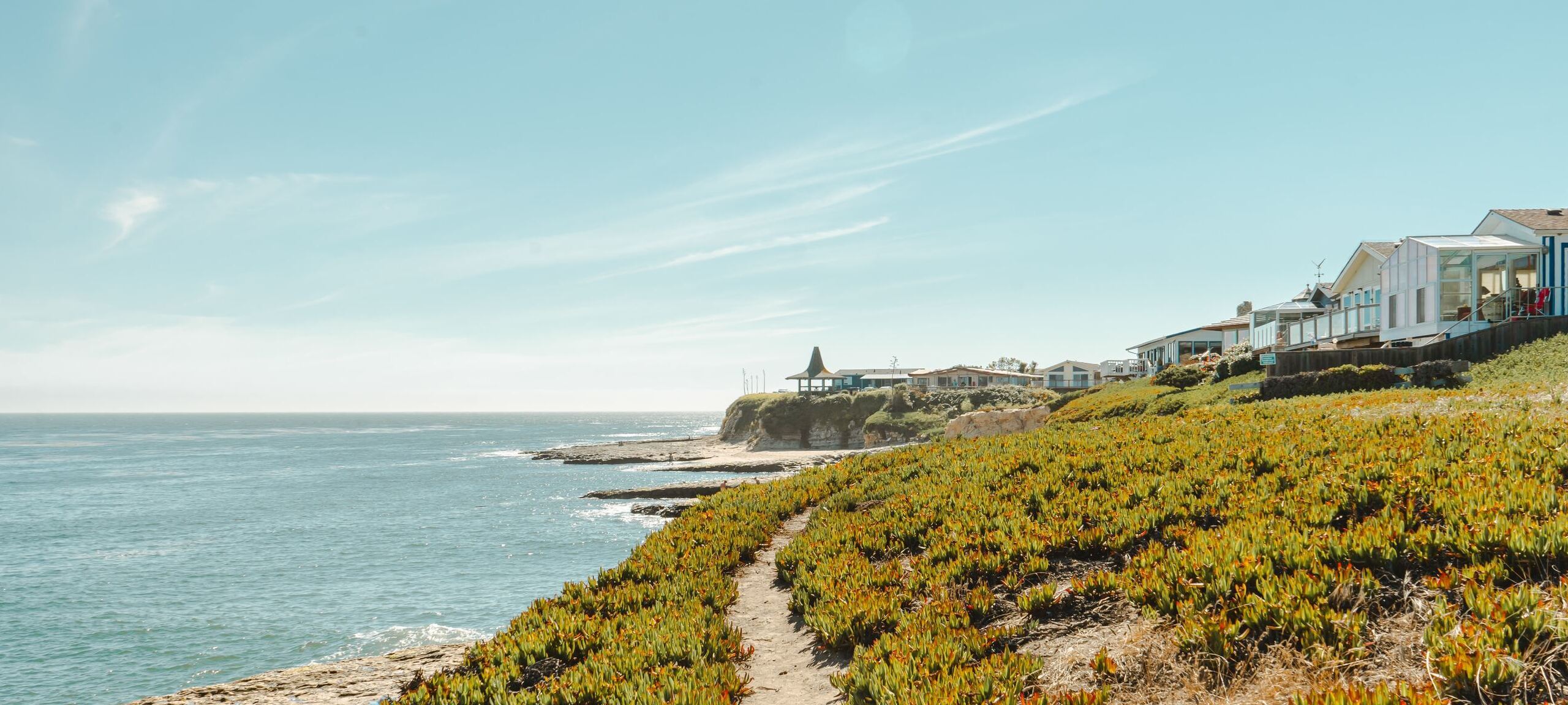 Beachfront luxury homes in Santa Cruz, CA from view of rocks. Photo by Taylor Cole on Unsplash