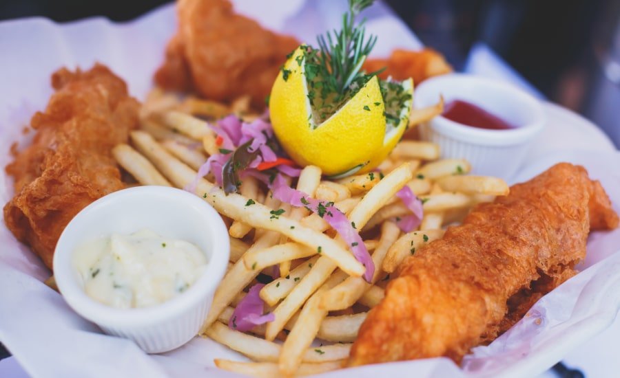 Fish and chips on plate with lemon and sauces