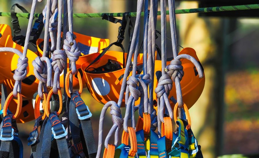 Ropes course equipment, including helmets and harnesses, hanging before use